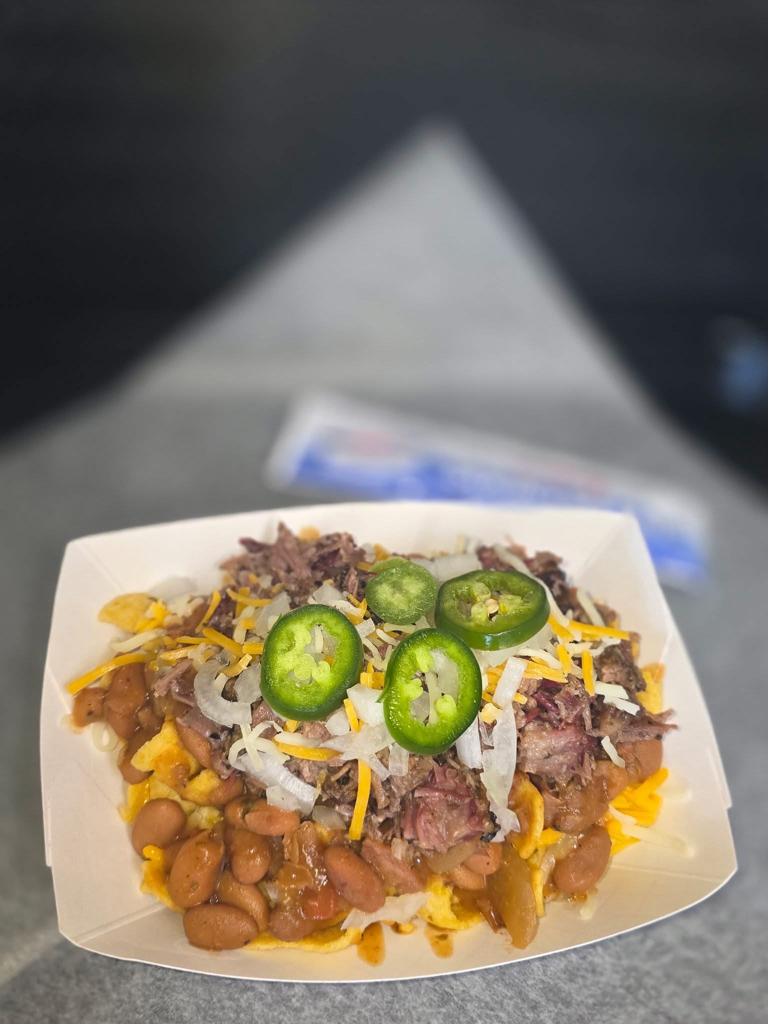 Loaded Frito pie with corn chips, beans, chopped brisket, shredded cheese, onions and jalapeños